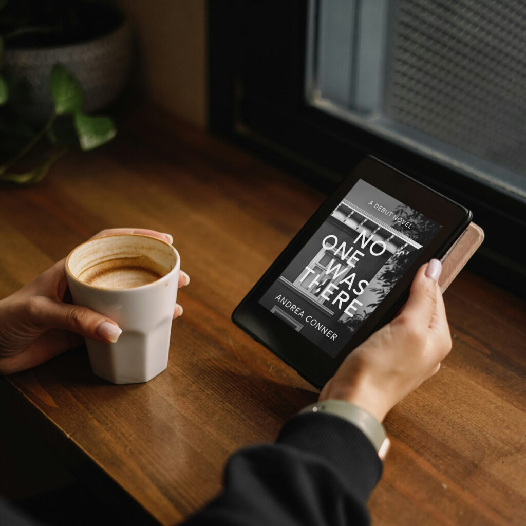 Feminine hands holding a cup of coffee in the left, a kindle e-reader in the right. The e-reader shows the cover of the book No One Was There by Andrea Conner