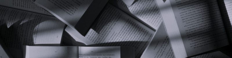 Image from unsplash showing a floor covered in opened book with a dim lighting